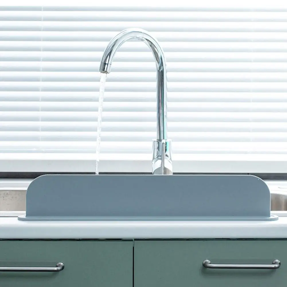 Gray kitchen sink with chrome faucet against a white window blind background