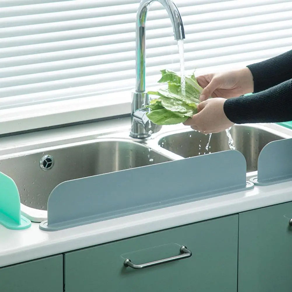 Person washing lettuce under a faucet with a kitchen sink and green cabinets in the background