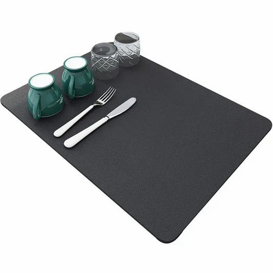 Black placemat with green cups, silverware, and glassware on a white background