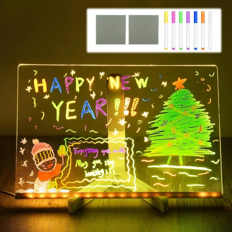 Light-up board with 'Happy New Year' and Christmas tree design, featuring colorful markers on a dark background.