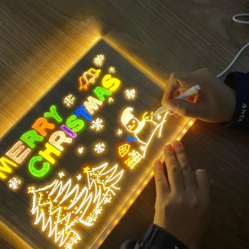 Person drawing on a light-up Christmas-themed board with colorful letters and a snowman.