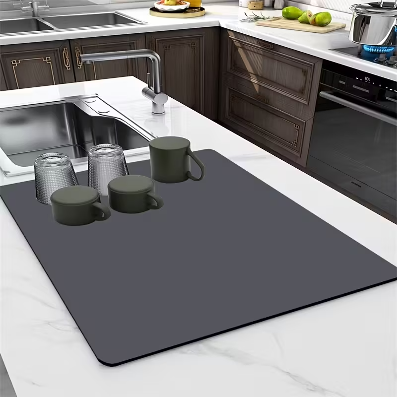Gray cutting board on a kitchen counter with mugs and glasses.